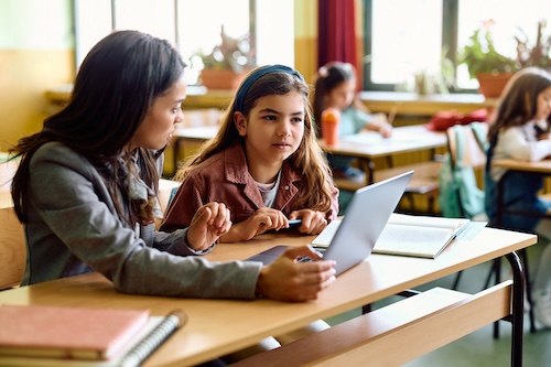 Teacher supporting a pupil using a laptop